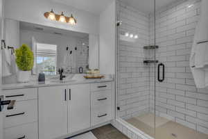 Bathroom with tile patterned flooring, visible vents, a shower stall, and vanity