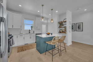 Kitchen featuring a sink, a kitchen bar, appliances with stainless steel finishes, and light wood finished floors