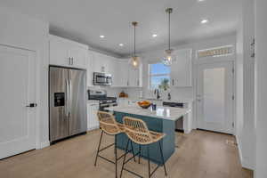 Kitchen featuring a kitchen bar, light wood-style flooring, backsplash, white cabinetry, and stainless steel appliances