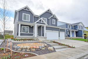 View of front facade with a porch, driveway, a garage, and board and batten siding