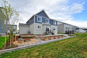 Back of property with a fire pit, board and batten siding, a patio, a residential view, and a yard