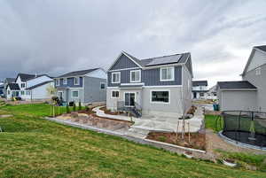 Back of property featuring a patio, a trampoline, a residential view, and roof mounted solar panels