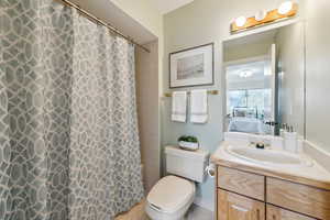 Bathroom with vanity, ensuite bath, curtained shower, tile patterned floors, and toilet
