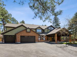 View of front of property featuring a garage, brick siding, driveway, and fence