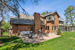 Back of property with a yard, a patio area, a chimney, fence, and brick siding