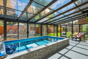 Pool featuring a fenced backyard, glass enclosure, and a patio
