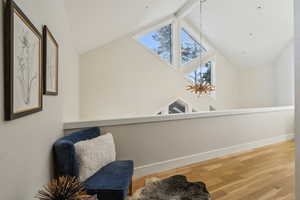 Living area featuring vaulted ceiling with skylight, baseboards, and wood finished floors