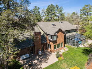 Back of house with a lawn, roof with shingles, a patio area, brick siding, and a lanai