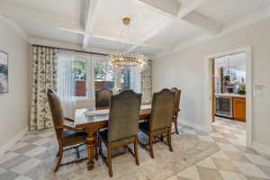 Dining area featuring coffered ceiling, wine cooler, an inviting chandelier, baseboards, and light floors