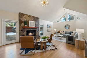 Living area featuring wood finished floors, high vaulted ceiling, a chandelier, and a tiled fireplace