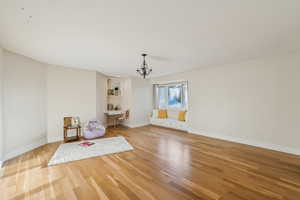 Unfurnished room with baseboards, an inviting chandelier, and light wood-style flooring
