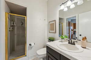 Full bath featuring tile patterned floors, vanity, toilet, and a shower stall