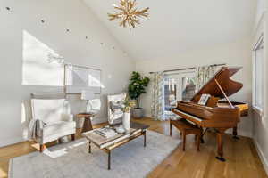 Sitting room with high vaulted ceiling, a healthy amount of sunlight, and wood finished floors