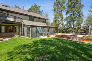Rear view of property with a garden, a yard, a pergola, and a sunroom