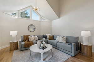 Living area featuring light wood-style floors, baseboards, and high vaulted ceiling