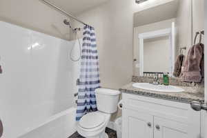 Full bathroom with toilet, vanity, and shower / bathtub combination with curtain