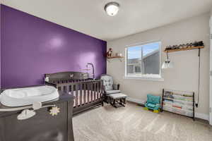 Bedroom featuring a nursery area, baseboards, and carpet