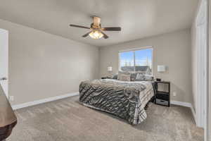 Carpeted bedroom featuring a ceiling fan, baseboards, and a textured ceiling