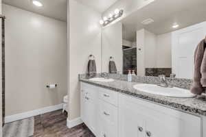 Full bathroom with double vanity, toilet, a stall shower, and a sink