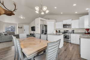 Dining space featuring recessed lighting, light wood-style flooring, lofted ceiling, and an inviting chandelier