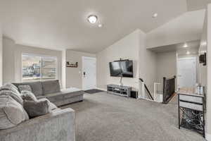 Living room featuring lofted ceiling, carpet, and baseboards