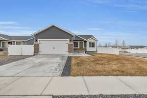 View of front of home featuring concrete driveway, an attached garage, fence, and a front lawn