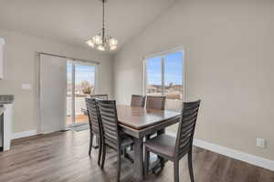 Dining area with baseboards, lofted ceiling, an inviting chandelier, and wood finished floors