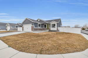 View of front of property with stucco siding, fence, concrete driveway, a front yard, and a garage