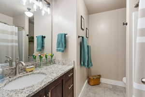 Full bathroom with toilet, granite countertops, curtained tub shower,  and vanity