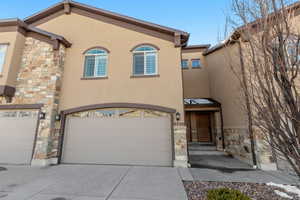 Multi unit property featuring stone siding, stucco siding, and driveway