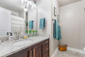 Bathroom featuring tile patterned flooring, vanity, and baseboards