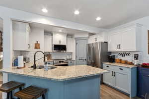 Kitchen featuring light wood-type flooring, a sink, a kitchen breakfast bar, stainless steel appliances, and a peninsula