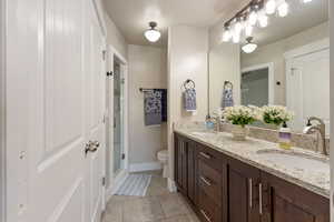 Primary bathroom with double sink vanity, bright lighting and walk-in shower