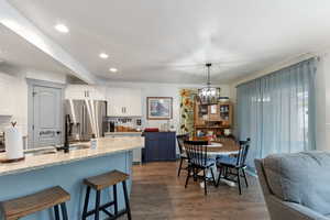 Kitchen with a breakfast bar, an inviting chandelier, a sink, light wood-type flooring, and stainless steel fridge