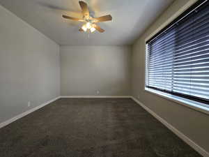 Master bedroom with ceiling fan, large window with blinds and walk in closet.