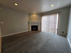 Living room with recessed lighting, carpet, a tiled fireplace, and sliding glass doors to the balcony
