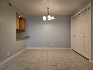 Dining area featuring an inviting chandelier, light tile patterned floors, baseboards, kitchen access and pantry.
