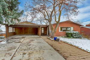 Ranch-style home with driveway, brick siding, and a carport
