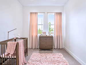 Carpeted bedroom featuring a crib and baseboards