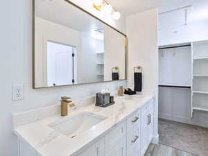 Full bath with a walk in closet, double vanity, and a sink
