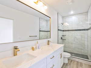 Bathroom with a shower stall, toilet, wood finished floors, and a sink
