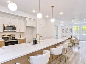 Kitchen featuring open floor plan, appliances with stainless steel finishes, a kitchen breakfast bar, and light wood-style flooring