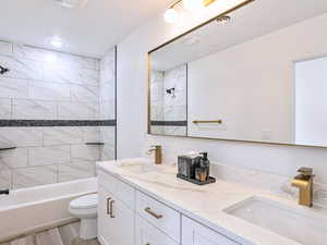 Bathroom featuring shower / bathing tub combination, double vanity, toilet, and a sink