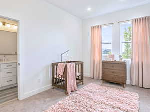 Bedroom with recessed lighting, a nursery area, baseboards, and light carpet