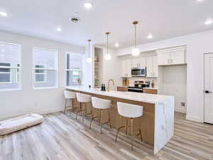 Kitchen with a peninsula, light wood-style floors, a breakfast bar area, and stainless steel appliances