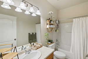 Full bathroom with shower / bath combo with shower curtain, toilet, and vanity