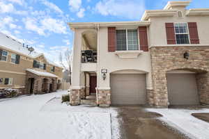 View of front of property with stone siding, stucco siding, and an attached garage