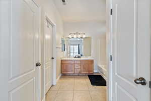 Full bath with tile patterned floors, a bath, double vanity, and a sink