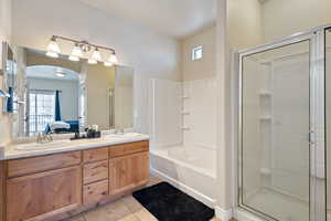 Ensuite bathroom featuring tile patterned floors, a stall shower, ensuite bath, and a sink