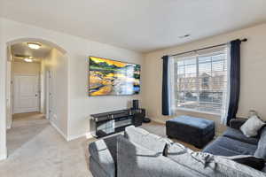 Living room featuring arched walkways, light colored carpet
